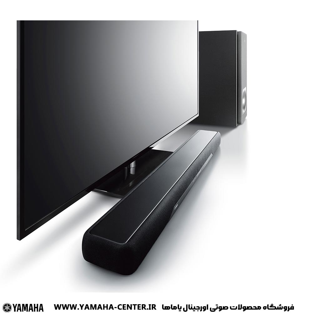 yamaha YAS-207 1 ساندبار یاماها YAS-207 در کنار تلویزیون و سابووفر بیسیم، با لوگوی یاماها.